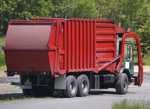 Skip hire truck and workers preparing a site for skip delivery
